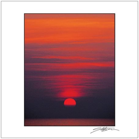 Vibrant sunset with rich orange and red hues against a dark horizon.